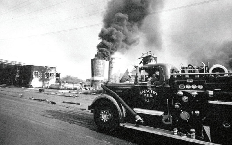 Crescent city fire truck from the 1960's with a large fire in front of them