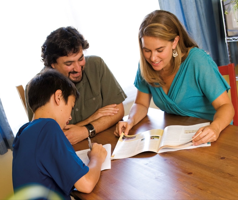 Mom and dad sitting at a table with a kid reading the magazine