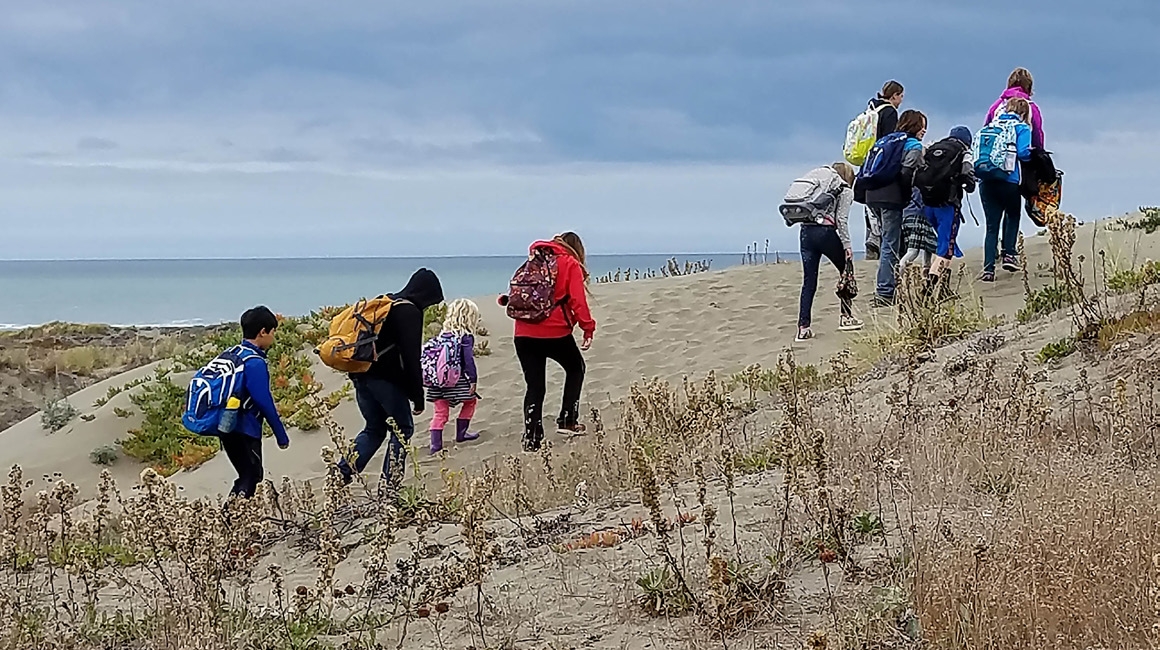 Students practicing their tsunami evacuation route by walking to the top of the sand dunes